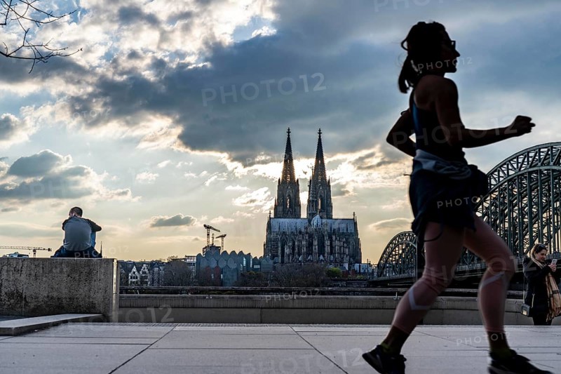Panorama, Skyline of Cologne, with the cathedral and the railway bridge, Hohenzollern Bridge, on the Rhine, sunset, jogger, North Rhine-Westphalia, Germany, Europe