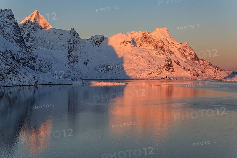 Snow-covered mountains reflected in the fjord at sunrise, winter, Reine, Moskenesoya, Lofoten, Norway, Europe