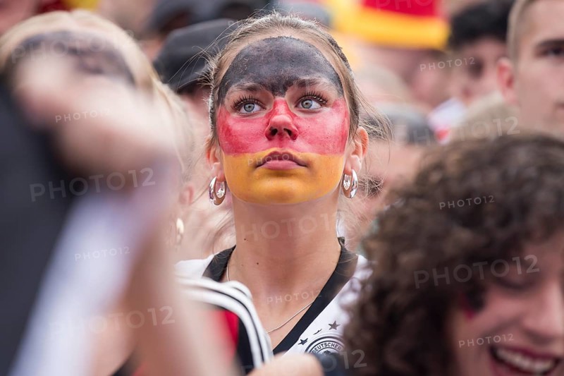 A woman wearing make-up in the German national colours watches the football match in the fan zone at the Brandenburg Tor during the quarter-final match between Germany and Spain at the European Football Championship, Berlin, 05.07.2024