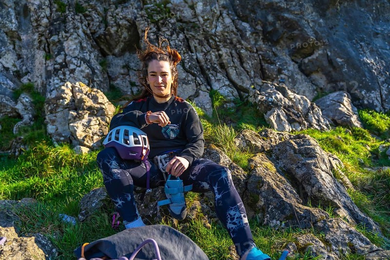 Young climber woman resting on a mountain after her climbing activity, checking her smartwatch