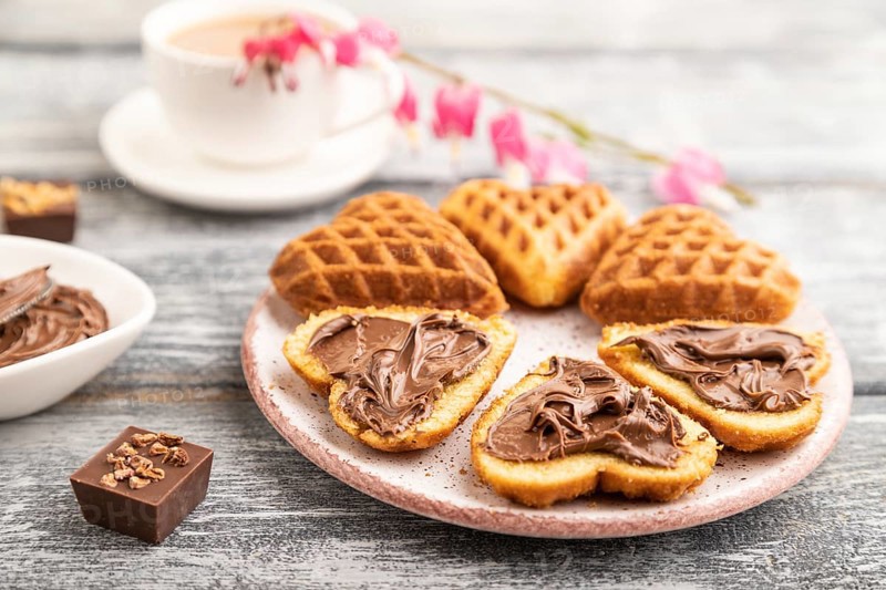 Homemade waffle with chocolate butter and cup of coffee on a gray wooden background. side view, selective focus, close up