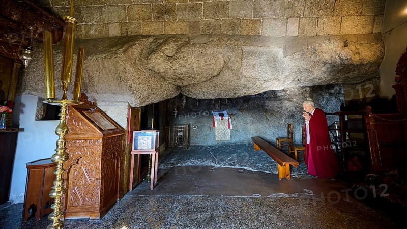 Praying woman in a sacred space with rock walls and an altar, rock grotto, Monastery tis Apokalipsis, Patmos, Dodecanese, Greek Islands, Greece, Europe
