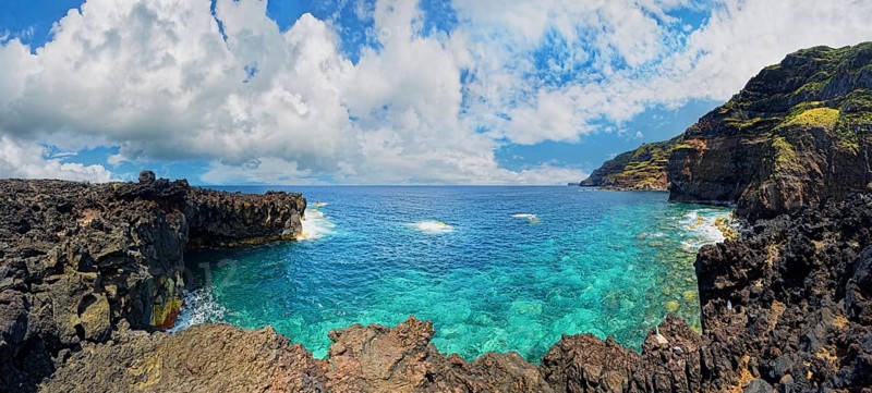 Panoramic view of a rocky lava coast with clear blue water and clouds in the sky, Termas da Ferraria, Sao Miguel Island, Azores, Portugal, Europe
