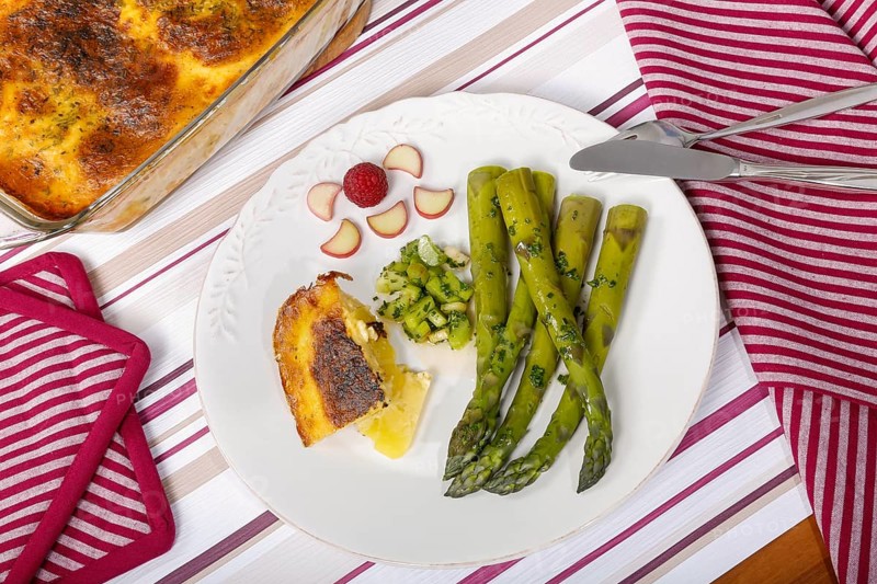 South German cuisine, green asparagus with rhubarb vinaigrette and potato gratin, healthy, vegetables, served on a plate, vegetarian, cutlery, knife, fork, casserole dish with gratin, gratinated, traditional cuisine reinterpreted, food photography, studio, Germany, Europe