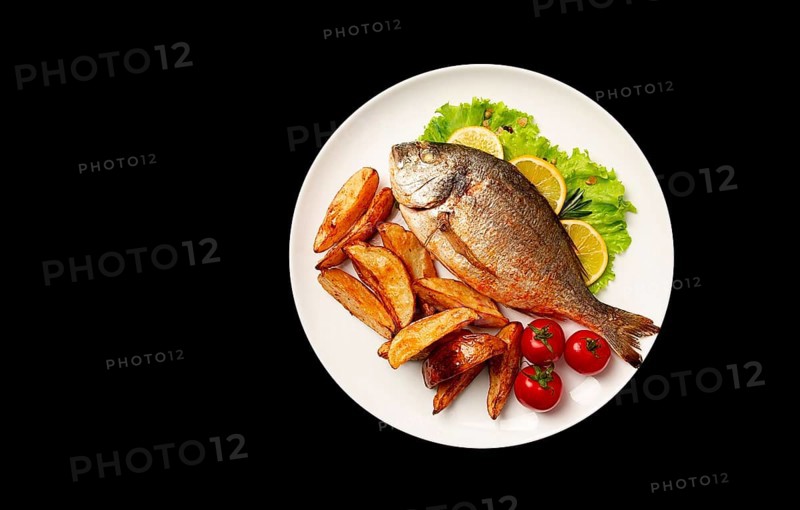 Fried Dorado fish, with potatoes, top view, on a black background, no people