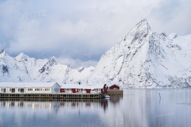 Rorbuer huts of Hamnoy at the fjord, snowy mountains in the background, Hamnøy, Reine, Moskenesøya, Lofoten, Norway, Europe