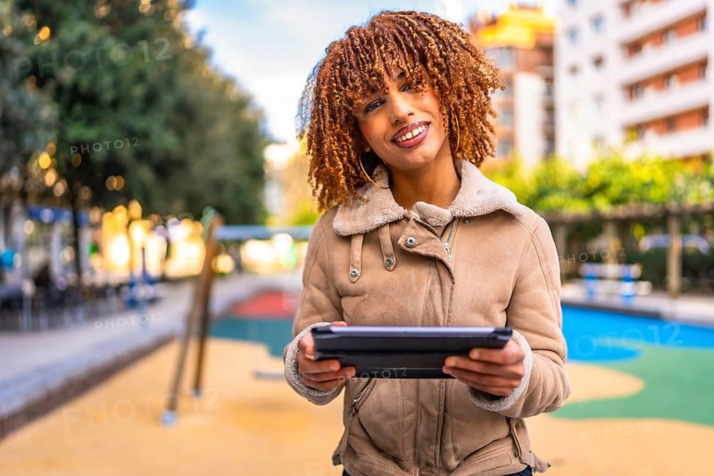 Frontal portrait of a beauty and happy latin woman holding digital tablet working outdoors