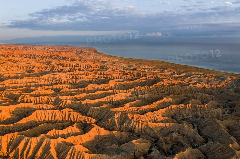 Landscape of eroded hills, badlands at sunset, Lake Issyk Kul in the background, aerial view, Canyon of the Forgotten Rivers, Issyk Kul, Kyrgyzstan, Asia