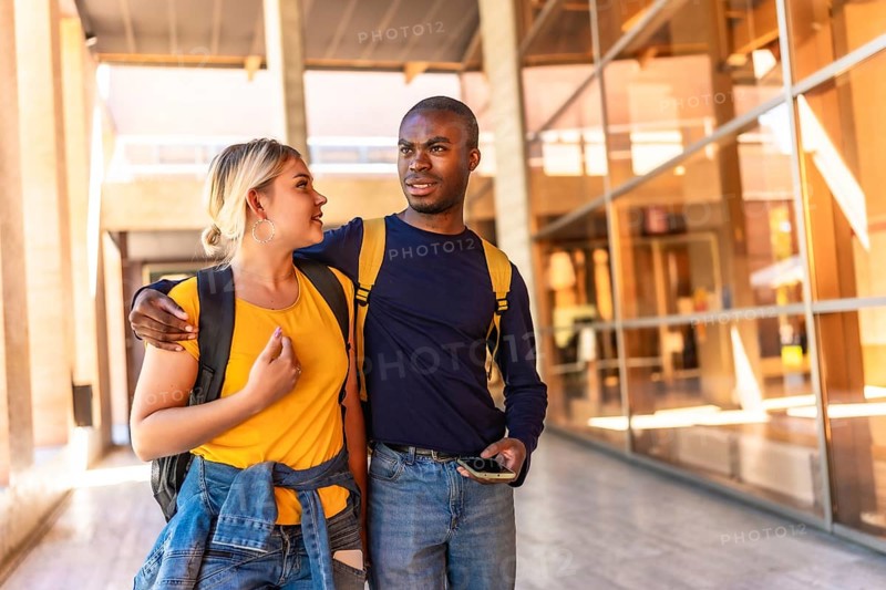 Multi-ethnic african and caucasian couple embracing walking along university