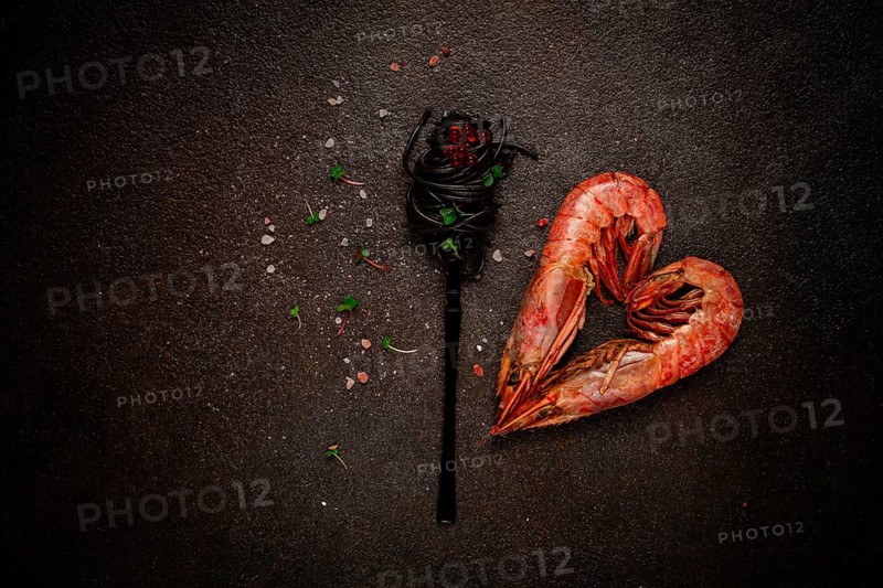 Black spaghetti, wrapped on a fork, langoustines in the shape of a heart, on the table, dish concept, dish background, top view
