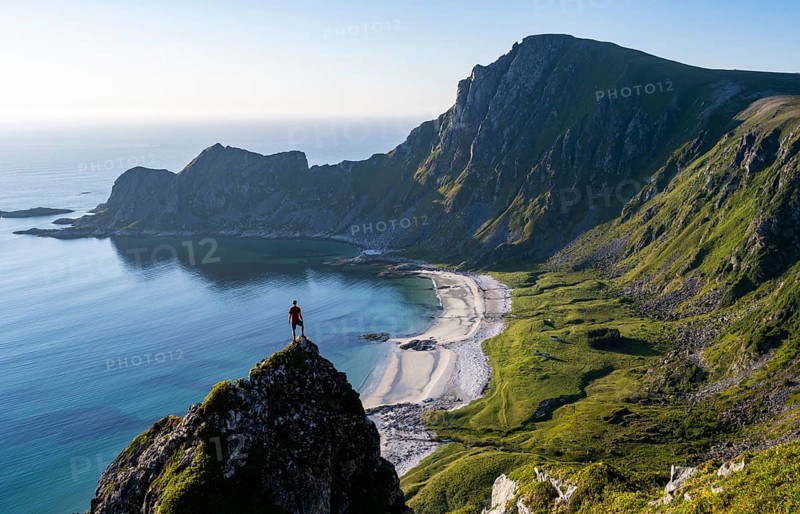 Climber on a rock, view of picturesque coastal landscape, steep coast with peak Måtind or Måtinden, Høyvika beach and sea, hike to the summit of Måtind, Andøya island, Vesterålen, Nordland, Norway, Europe