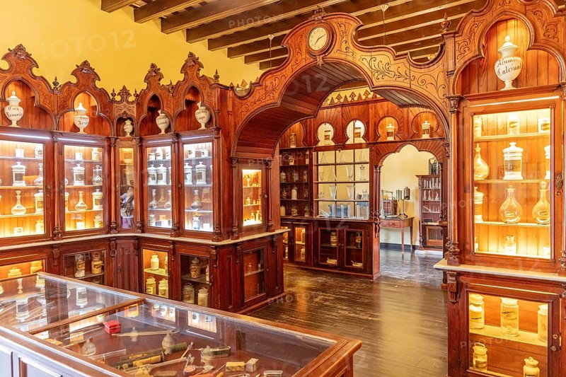 Antique apothecary museum with illuminated wooden display cases full of jars, Jerez