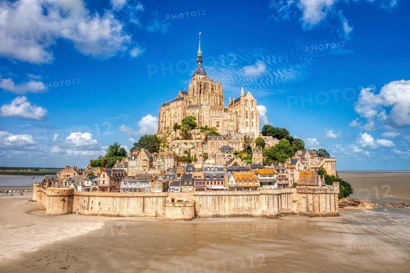 Majestic abbey on a mountain in a vast landscape under a partly cloudy sky, Le Mont-Saint-Michel