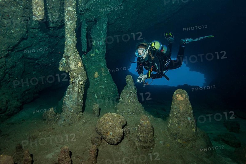 Scuba diver female diver swimming dives in entrance area of underwater cave stalactite cave underwater with stalactites stalagmite formations off east coast of Majorca, Mediterranean Sea, Balearic Islands, Majorca, Spain, Europe