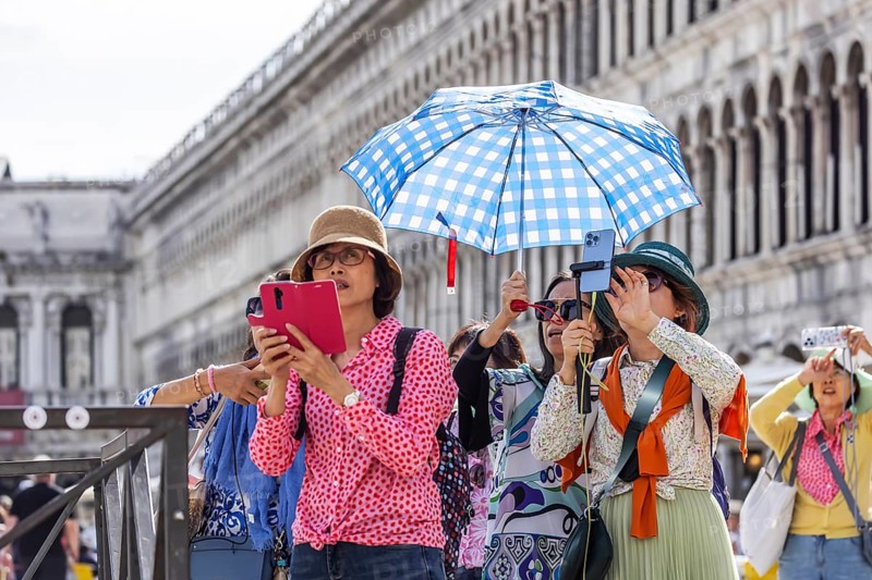 Tourists from Asia with mobile phones and parasols taking photos. Souvenir photo of St Mark's Square, Venice, Venice, Italy, Europe