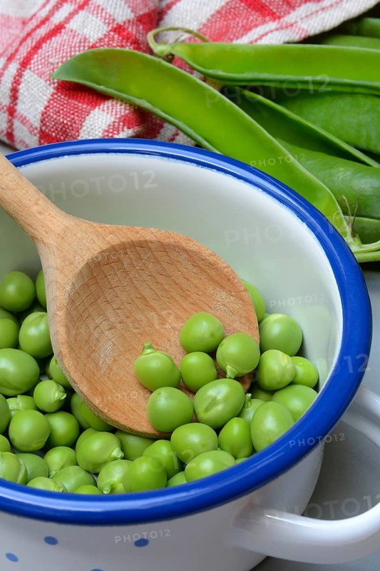 Fresh green peas in pot with wooden spoon, Pisum sativum