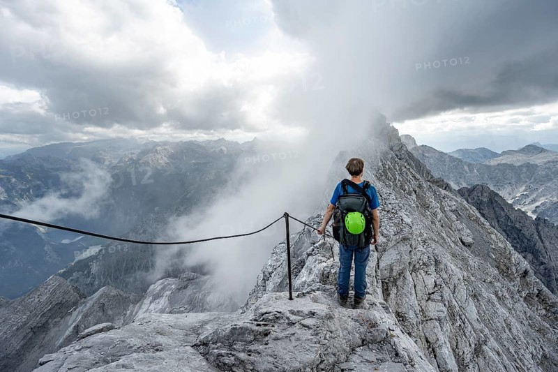 Mountaineer on a narrow rocky ridge on a steel cable, Watzmann crossing to Watzmann Mittelspitze, view of mountain panorama, Berchtesgaden National Park, Berchtesgaden Alps, Bavaria, Germany, Europe