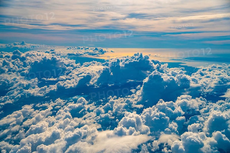 Golden hour sunlight illuminates a vast expanse of fluffy white clouds over coron island, philippines, creating a breathtaking aerial view