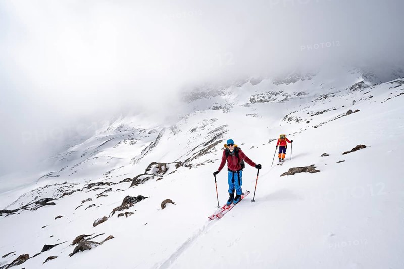 Two ski tourers in a wintry mountain landscape with cloudy mountain peaks, ascent to Piz Laviner, Grisons Haute Route, Albula Alps, Rhaetian Alps, Grisons, Eastern Switzerland, Switzerland, Europe