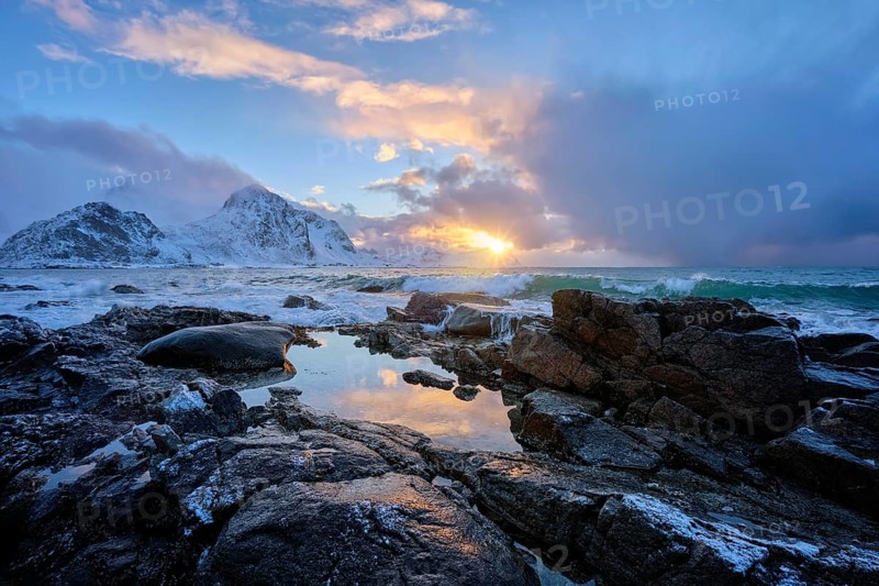 Beach of Norwegian sea on rocky coast in fjord on sunset in winter. Vareid beach, Lofoten islands, Norway, Europe
