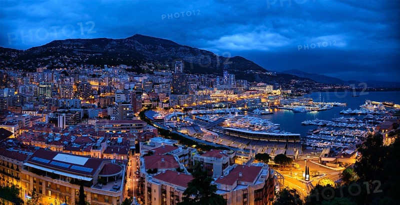 Aerial panorama of Monaco Monte Carlo harbour and illuminated city skyline in the evening blue hour twilight. Monaco Port night view with luxurious yachts