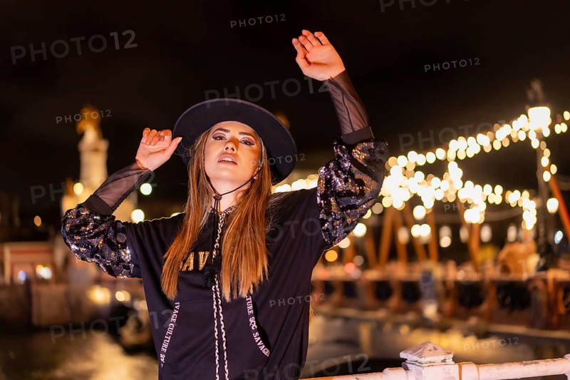 Christmas lights in the city, Caucasian blonde girl dressed in black with a hat on an illuminated bridge, winter lifestyle
