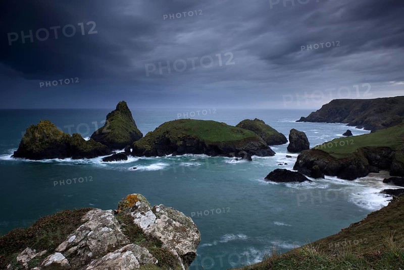 Dramatic clouds on rocky coast, rising rain shower over rocky islands with foaming surf, Kynance Cove, The Lizard, Cornwall, England, Great Britain