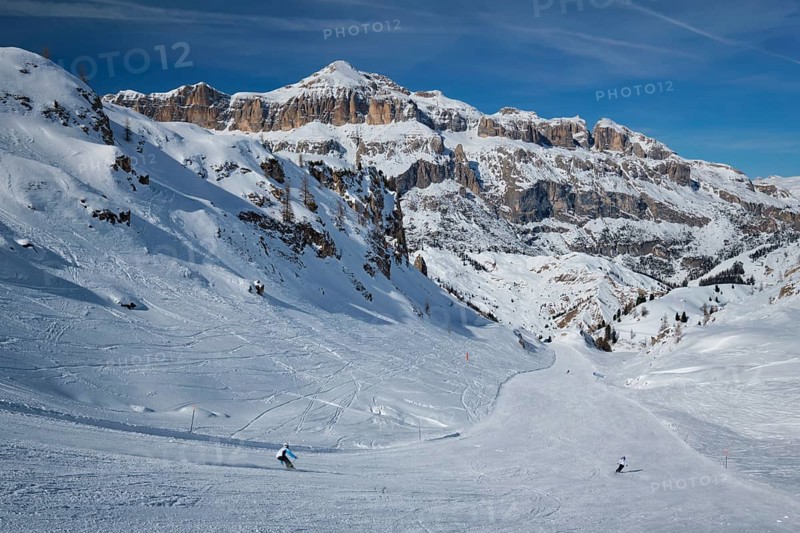 View of a ski resort piste with people skiing in Dolomites in Italy. Ski area Arabba. Arabba, Italy, Europe