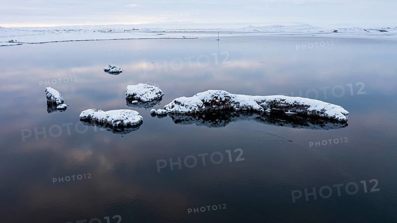 Snow-covered small islands overgrown with bushes in Lake Myvatn, at blue hour, Kalfaströnd, drone shot, Northern Iceland Eyestra, Iceland, Europe
