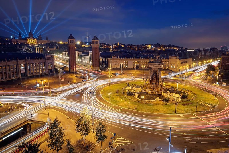 View Placa d'Espanya, Plaza de Espana, the Spanish Square in Barcelona, Catalonia, Spain with city traffic in the evening blue hour with light trails