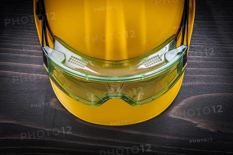 Safety glasses and building helmet on vintage wooden board