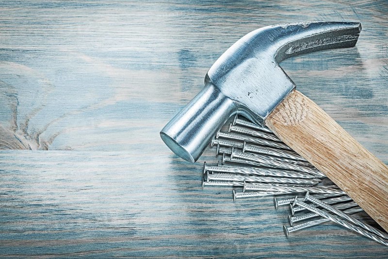 Claw hammer nails on wooden board construction concept