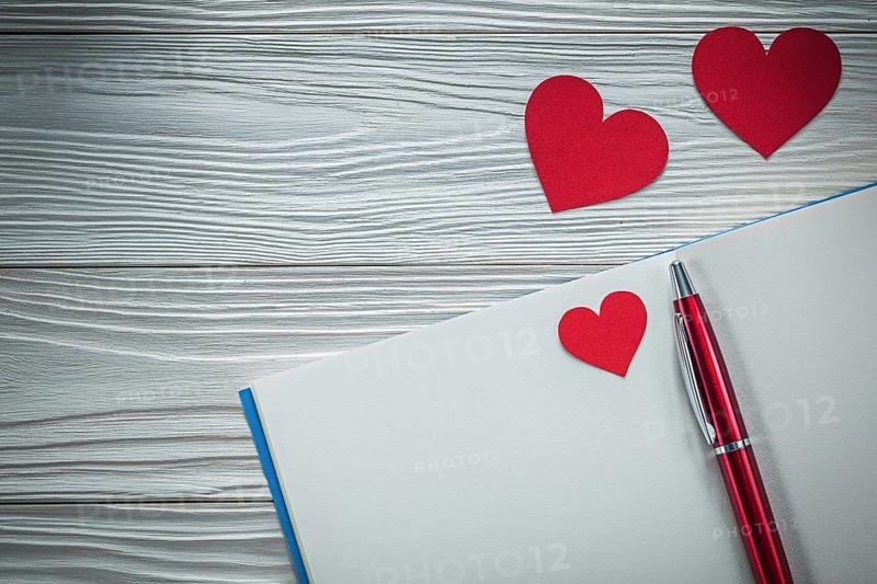 Red hearts ballpoint pen notebook on wooden board education concept