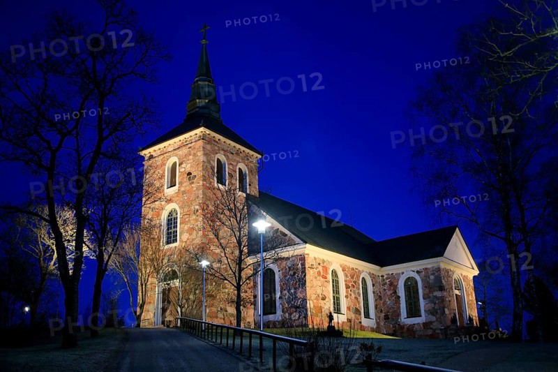 Illuminated Uskela Church, designed by Finnish architect C. L. Engel and built 1832, in winter nightfall. Salo, Finland. January 2020