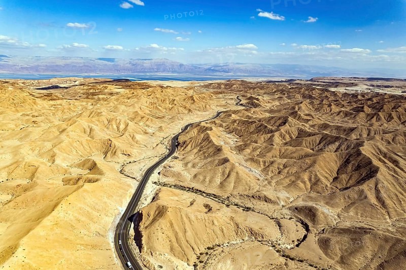 Desert on the shores of the Dead Sea. Asphalt highway meanders among the hills. Dead Sea mud has healing properties. Bird's eye view. Israel