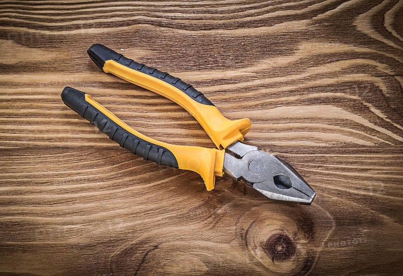 Gripping tongs on vintage wooden board construction concept