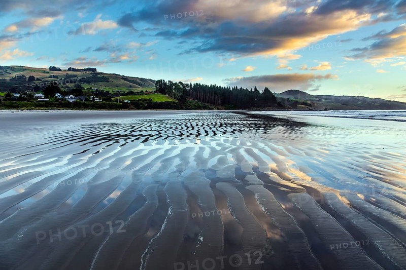 New Zealand, Pacific Coast. Low tide. Strips of sand and water left by the ocean tide. Sunrise over the ocean. The concept of artistic photography. Artistic postal and greeting card, Oceania