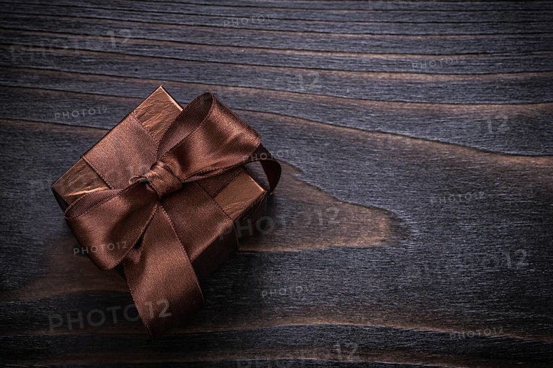Boxed present with brown bows on vintage wood board