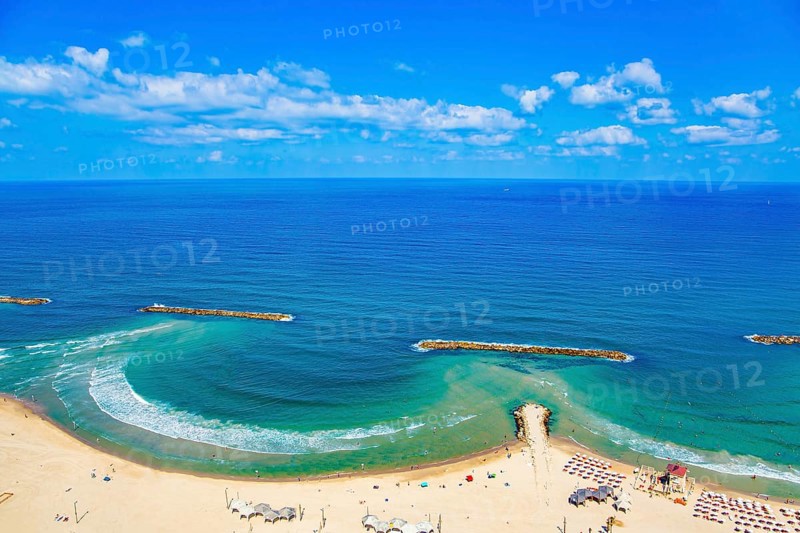 Magnificent sandy beach in Tel Aviv. Photo taken from the roof of a high-rise hotel. The blue waters of the Mediterranean attract tourists. Breakwaters reduce surf. Israel