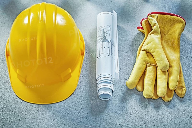 Building helmet protective gloves blueprints on concrete surface construction concept