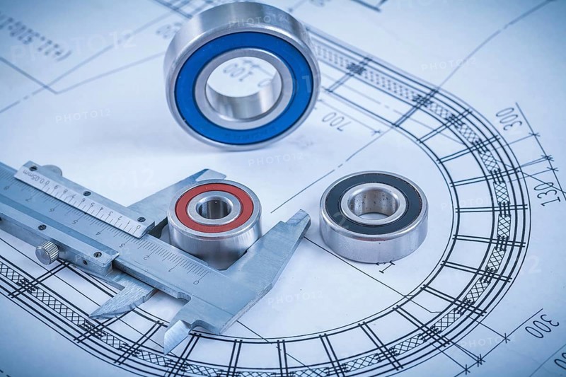 Metal roller bearings and trammel caliper on blueprint construction concept