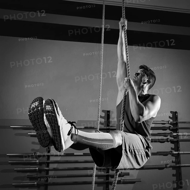 Rope Climb exercise man workout at gym climbing