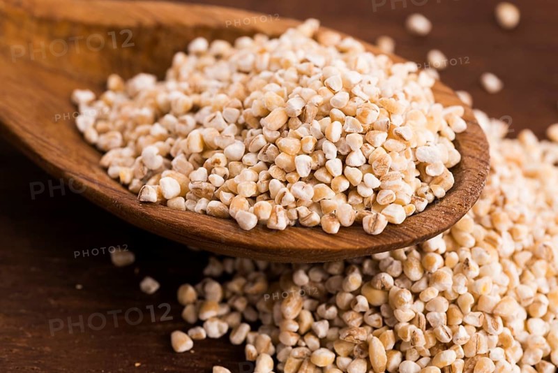 Barley groats on wooden spoon