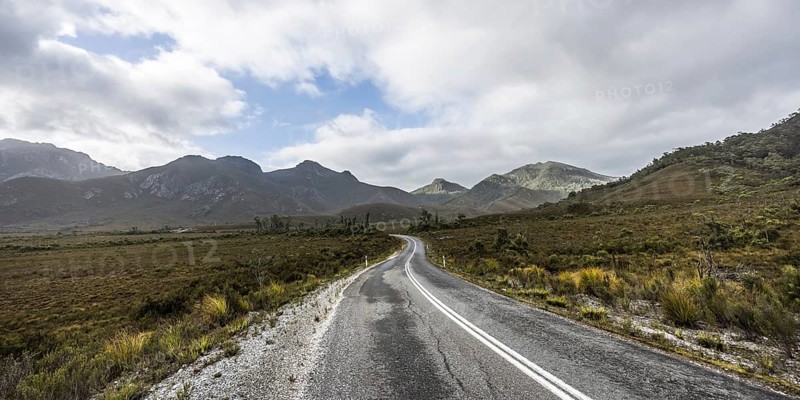 The picturesque Gordon River Rd at the Sentinel range of mountains near Bitumen Bones Sculpture on a cool wet summer's morning in Southwest National Park, Tasmania, Australia, Oceania