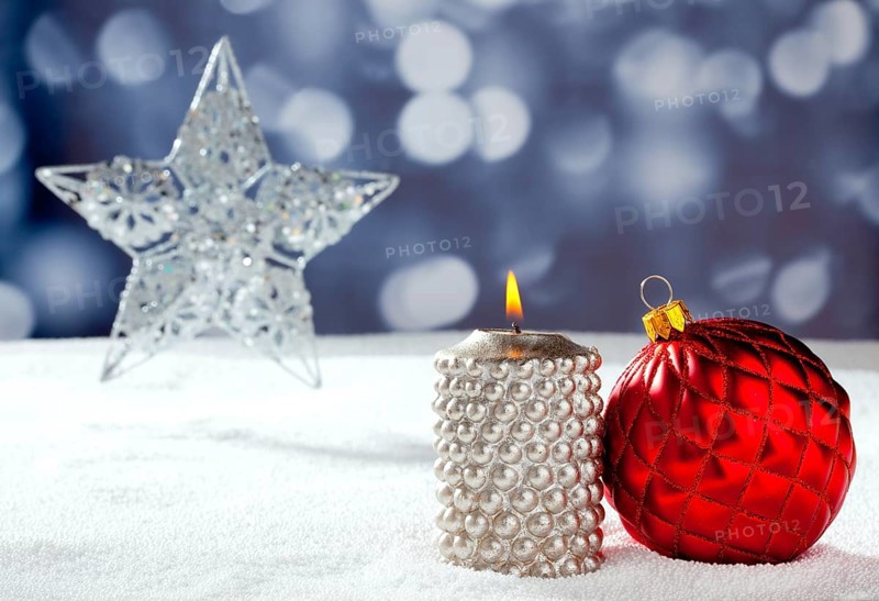 Christmas card of silver star bauble and candle on snow and blue background