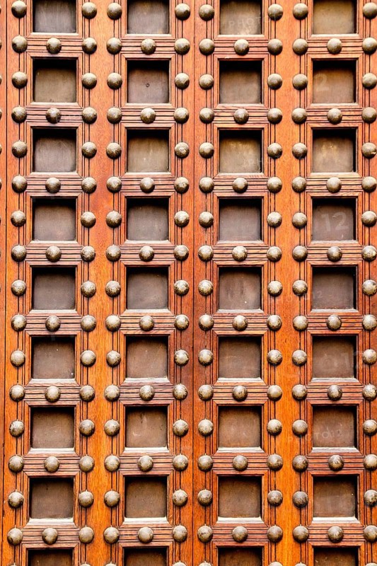 Ancient church castle wooden door with nails and little square shapes in spain