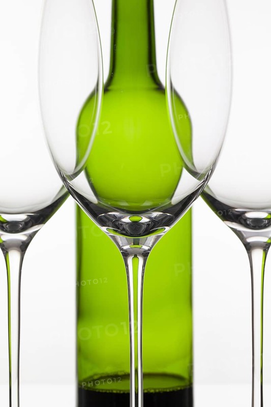 Three empty glasses of wine and green bottle on the white background