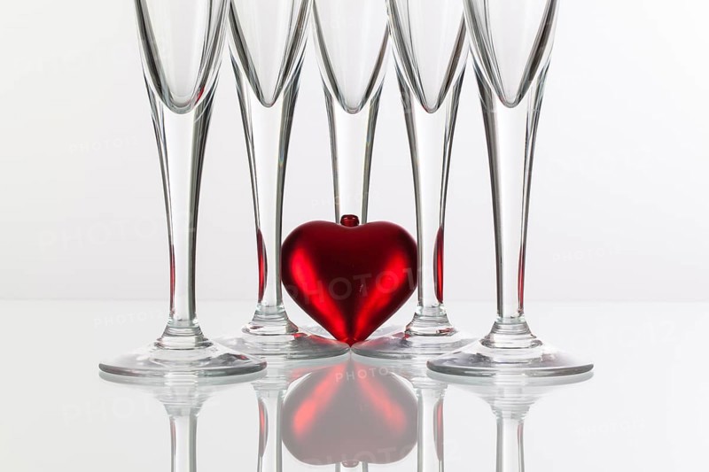 Five champagne glasses and red heart on a glass plate