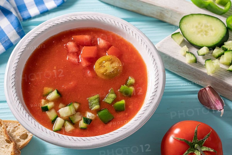 Gazpacho Andaluz is an Andalusian tomato cold soup from Spain with cucumber, garlic, pepper on light blue background