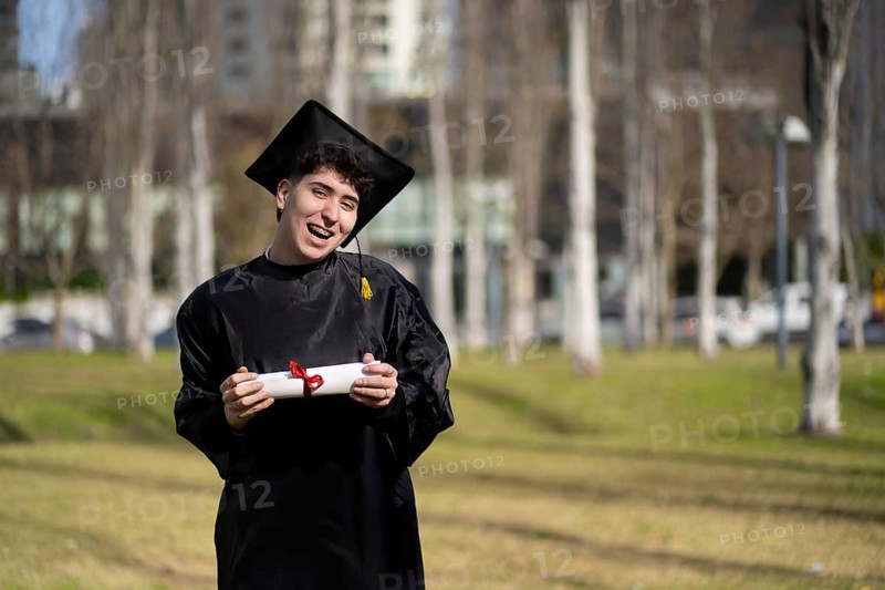 Young gay man recent graduated, dressed in cap and gown, showing off his degree celebrating
